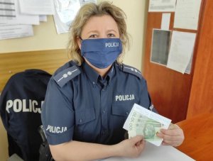 policjantka siedzi przy biurku i trzyma banknoty