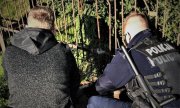 dwaj policjanci kucają przy ogrodzeniu gdzie zakleszczyła się sarna