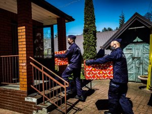 dwóch policjantów niesie po schodach paczki z prezentami