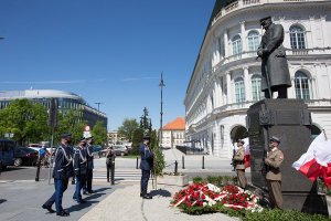po prawej stronie pomnik Józefa Piłsudskiego, przy pomniku stoją na warcie żołnierze, pod pomnikiem leżą wieńce kwiatów, z lewej stronie policjanci