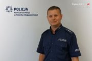 umundurowany policjant na tle ściany z napisem Komisariat Policji w Rybniku - Boguszowicach