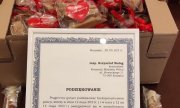 dyplom z podziękowaniami dla policjantów, oparty o karton ze słodyczami