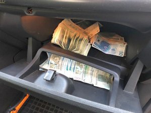 Na zdjęciu widoczne są pieniądze ukryte w schowku samochodowym&quot;&gt;