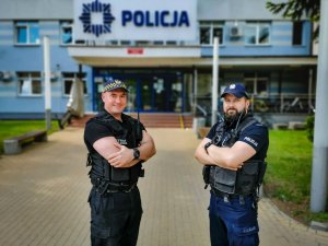 po lewej stronie funkcjonariusz Straży Miejskiej, po prawej białostocki policjant. Mundurowi stoją na tle Komendy Miejskiej Policji w Białymstoku