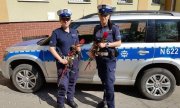 dwie umundurowane policjantki ruchu drogowego przed radiowozem, w ręku trzymają róże