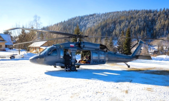 Policyjny helikopter na zaśnieżonym górskim lądowisku.