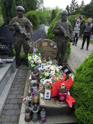 dwaj żołnierze przy grobie, w tle dwaj mężczyźni