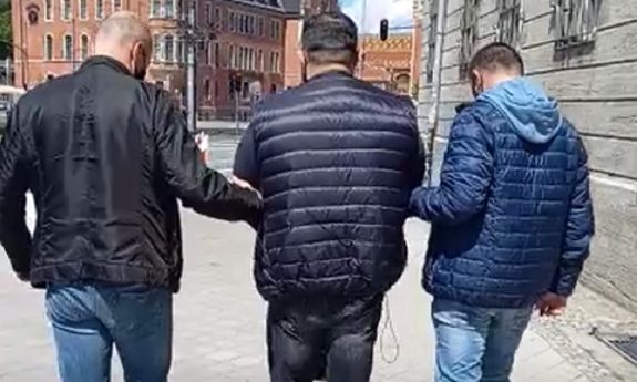 dwaj policjanci ubrani po cywilnemu prowadzą zatrzymanego - widok z tyłu