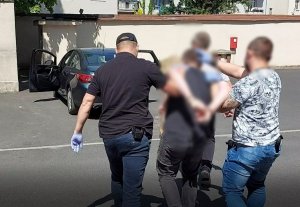 policjanci ubrani po cywilnemu prowadzą zatrzymanego