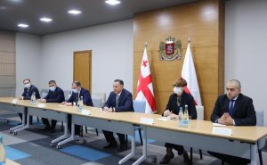Pięciu mężczyzn w garniturach i jedna kobieta, siedzą za stołami podczas spotkania w siedzibie Ministerstwa Spraw Wewnętrznych Republiki Gruzji, z tyłu widoczne są flagi Polski i Gruzji