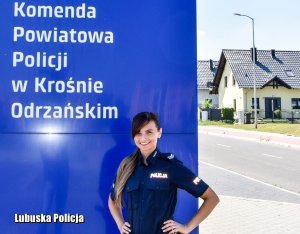 Umundurowana policjantka stojąca przy banerze z napisem Komenda Powiatowa Policji w Krośnie Odrzańskim