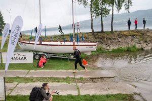Policyjny triathlonista z Myślenic wychodzi z wody, w tle widać łódź, fotografów, innych zawodników oraz osoby przyglądające się