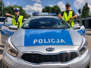 Radiowóz oznakowany oraz dwoje policjantów ruchu drogowego