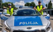 Radiowóz oznakowany oraz dwoje policjantów ruchu drogowego