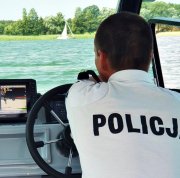 Policjant na łodzi motorowej płynie do żaglówki w trzcinowisku