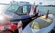 &quot;Łódź policyjna przy przewróconym jachcie na jeziorze, obok łódź WOPR, plecy ratownika&quot;&gt;