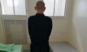 Mężczyzna stojący tyłem w pomieszczeniu dla osób zatrzymanych dąbrowskiej komendy Policji