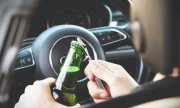 Kierowca otwierający butelkę alkoholu za kierownicą