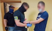 zdjęcie kolorowe: nieumundurowany policjant zakłada kajdanki na ręce mężczyźnie zatrzymanemu za śmiertelne potracenie 19-letniej kobiety