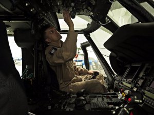 Policyjny mechanik lotniczy dokonuje przeglądu przed lotem wyposażenia kabiny pilotów śmigłowca S70i Black Hawk.