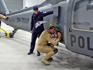 Wyprowadzanie śmigłowca S70i Black Hawk na płytę startową. Na zdjęciu członek załogi dokonujący ostatnich sprawdzeń aparatury w bocznym luku maszyny oraz zastępca Komendanta Głównego Policji nadinsp. Roman Kuster.