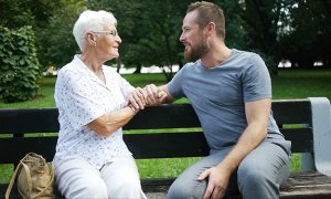 Mężczyzna rozmawia ze starszą kobietą na ławce w parku