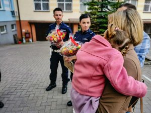 policjant i policjantka z prezentami, matka z dzieckiem na rękach
