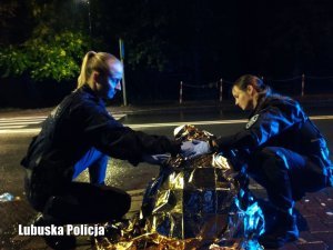 dwie policjantki przykrywają kocem medycznym poszkodowanego