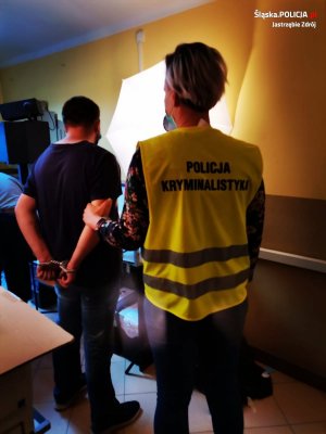 policjantka w żółtej kamizelce z napisem na plecach Policja kryminalistyka, stoi z zatrzymanym