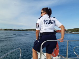 umundurowana funkcjonariuszka Policji stojąca na łodzi - widok z tyłu