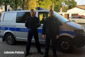dwaj  umundurowani policjanci przy radiowozie