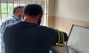 policjant wykonuje daktyloskopię sprawcy oszustwa