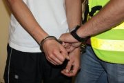 policjant zakłada zatrzymanemu kajdanki na ręce