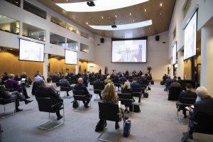 Europejska Konwencja Szefów Policji (EPCC)  państw Unii Europejskiej w Hadze- zebrani siedzą na krzesłach w sali z zachowaniem dystansu i w maseczkach na twarzach - widok z tyłu a przed nimi i po bokach widać telebimy na których widnieje przemawiający mężczyzna