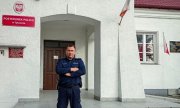 Umundurowany policjant stoi przed budynkiem Policji w Tykocinie
