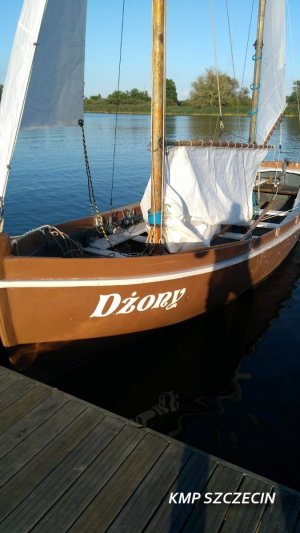 Zwodowana łódź masztowa z napisem koloru białego nazwą Dżony