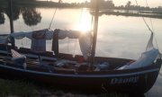 Zwodowana łódź masztowa, w tle zachód słońca