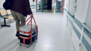 Szpitalny korytarz. Mężczyzna ciągnie lodówkę z sercem do przeszczepu