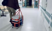 Szpitalny korytarz. Mężczyzna ciągnie lodówkę z sercem do przeszczepu