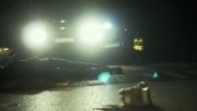 na pierwszym planie leżąca na jezdni osoba w tle światła samochodu radiowóz oraz policjanci całość mało ostra, zdjęcie zdobione o zmroku