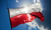 flaga Polski powiewa na wietrze, w tle niebo z chmurami