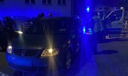 Pora nocna, samochód i radiowóz stoją, obok stają policjanci i osoby