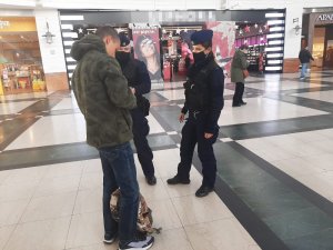 dwaj policjanci kontrolują mężczyznę, wnętrze galerii handlowej w tle ludzie