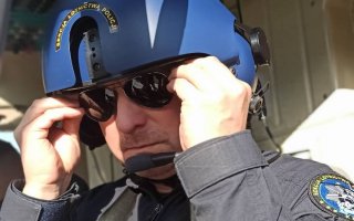 Policyjny pilot śmigłowca poprawiający okulary.