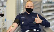 Policjant oddający krew z uniesionym kciukiem