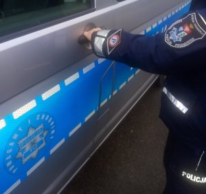 Umundurowany policjant otwiera drzwi radiowozu