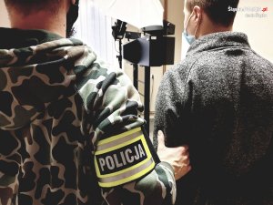 policjant i zatrzymany w pomieszczeniu do daktyloskopii i identyfikacji - widok z tyłu
