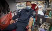 policjant podczas oddawania krwi w krwiobusie