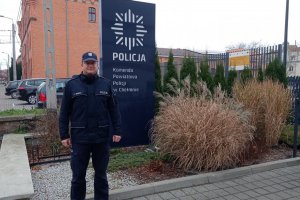 Policjant stojący przed budynkiem komendy Policji