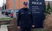 Policjant stojący przed budynkiem komendy Policji w Chełmnie